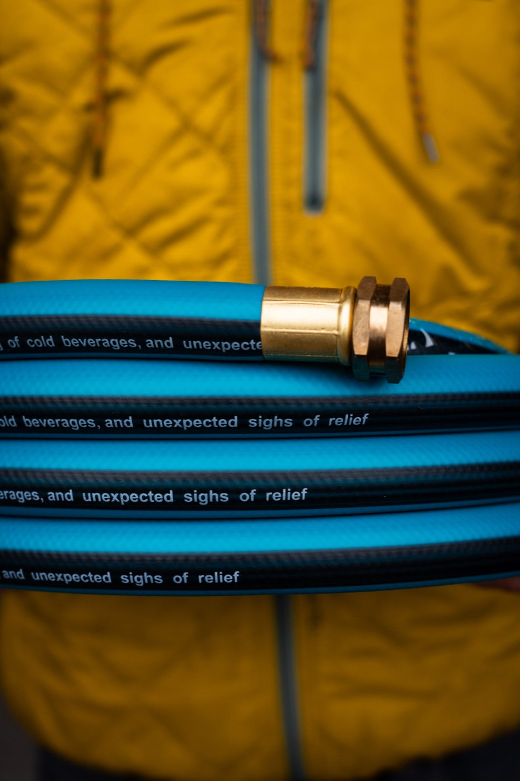 Close-up of a coil of THE HOSE — woven jacket and solid brass coupling