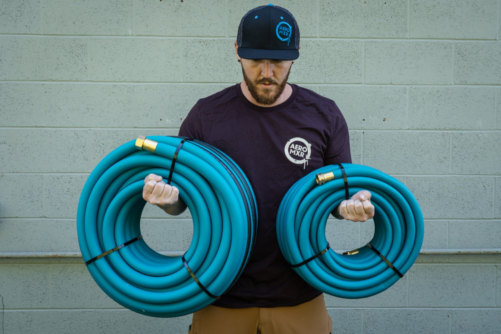 Holding two full coils of THE HOSE, brass ends out